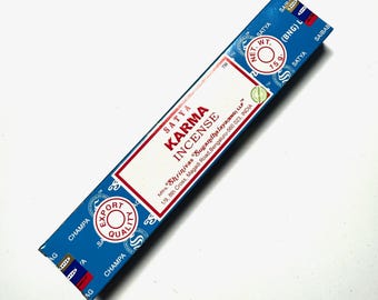May include: Blue and white box of Satya Karma incense sticks. The box has the text "Satya Karma Incense" and "Mirs. Shrinivas Sugandhalaya (BNG) LLP 1/9, 8th Cross, Magadi Road, Bengaluru-560 023, INDIA" printed on it.