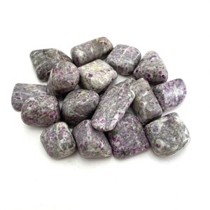 May include: A pile of tumbled ruby in zoisite stones. The stones are a mix of grey and pink with a speckled pattern.