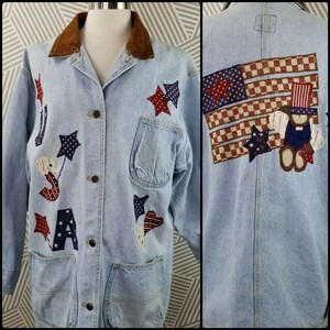May include: A light blue denim jacket with a brown corduroy collar. The jacket is decorated with red, white, and blue patches in the shape of stars, hearts, and the letters "USA". The back of the jacket features a large American flag patch with a teddy bear wearing a red, white, and blue hat.