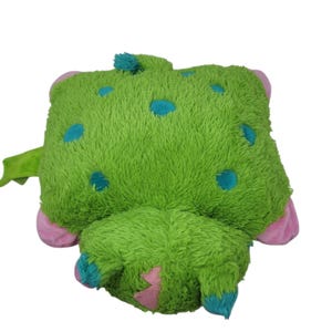 Puede incluir: Un peluche verde con lunares azules, detalles rosas y una peque&ntilde;a ala verde. El juguete tiene una textura peluda y un dise&ntilde;o caprichoso, perfecto para el juego de los ni&ntilde;os o como objeto decorativo.
