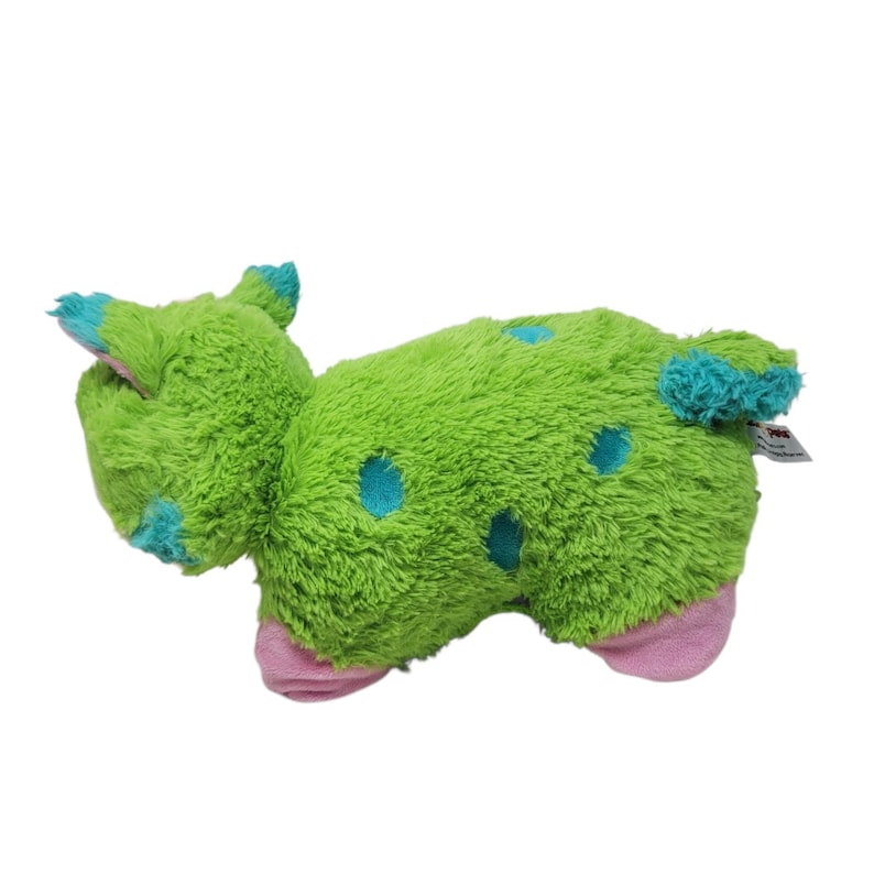 Puede incluir: Un peluche verde con forma de criatura, con lunares y detalles azules. Tiene pies y orejas rosas. El juguete est&aacute; hecho de un material suave y afelpado.