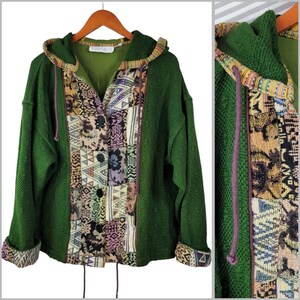 Puede incluir: Una chaqueta con capucha de color verde bosque confeccionada en tejido de punto texturizado, con cierre de botones y un panel vertical de tela de tapiz tejida multicolor. La prenda incluye mangas largas con puños doblados y capucha con cordones morados.