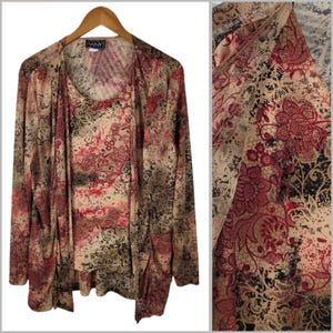 May include: A two-piece women's outfit featuring a long-sleeved, open-front cardigan and a matching tank top. The set is adorned with a floral and lace pattern in shades of beige, red, and black. The brand name "VANY" is visible on the tag.