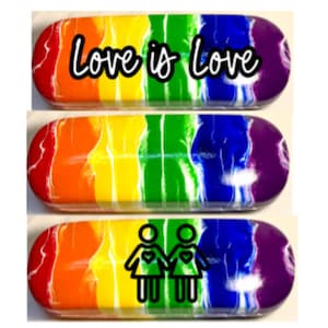 May include: Two rainbow-colored glasses cases with a white swirl design. One case has the text "Love is Love" in black lettering. The other case has a black silhouette of two people holding hands with hearts in their chests.