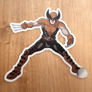 May include: A brown and black cartoon Wolverine character with claws and a red X on his belt. The character is in a fighting pose with his arms and legs spread out.