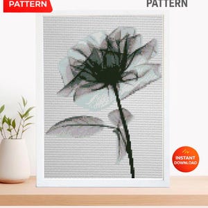 May include: A framed cross-stitch pattern featuring a black and white floral design. The image includes the text "CROSS STITCH PATTERN" and "PDF PATTERN". A red banner indicates "INSTANT DOWNLOAD". The artwork is displayed on a wooden surface.
