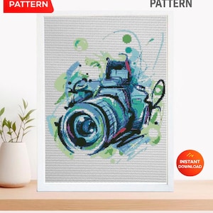 May include: Cross stitch pattern featuring a colorful camera design. The artwork uses shades of blue, green, and purple. The words "PDF Pattern" and "Instant Download" are displayed on the image.