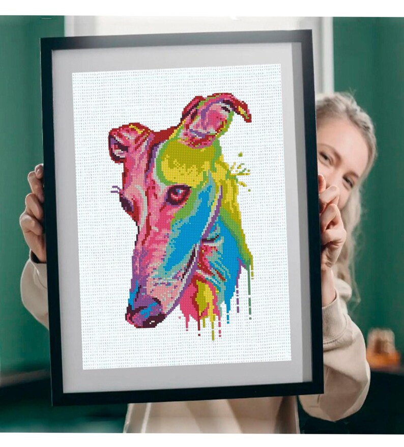 May include: A framed wall art piece featuring a pixelated, multi-colored portrait of a greyhound dog. The artwork uses vibrant shades of pink, yellow, green, and blue to depict the animal's head, with paint-like drips extending from the neck.