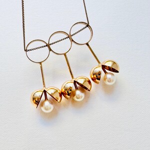 May include: Gold necklace with three open circles and three dangling gold spheres with pearls inside.