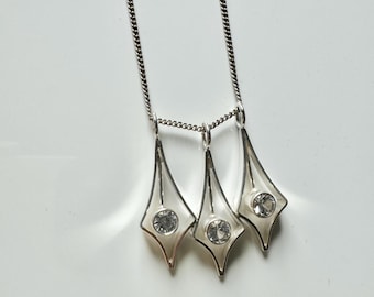 May include: A silver necklace with three pendant charms. Each charm is a silver diamond shape with a clear crystal in the centre.