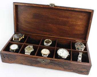 May include: A wooden watch box with a dark brown finish, open to reveal ten compartments lined with black velvet. Several watches with various band and face designs are displayed inside the box.
