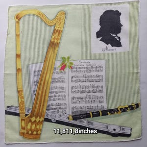 Könnte beinhalten: Ein Taschentuch mit musikalischem Thema. Es zeigt eine goldene Harfe, eine Flöte, Noten und eine Silhouette von Mozart. Die Texte "Serenade" und "Mozart" sind ebenfalls sichtbar. Die Abmessungen betragen 300.015,7 cm.