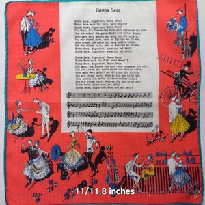 Puede incluir: Pañuelo rojo y blanco con borde turquesa, con ilustraciones de parejas bailando y notas musicales. Se muestra el texto "Buona Sera", junto con letras en alemán. El pañuelo mide 28 x 30 cm.