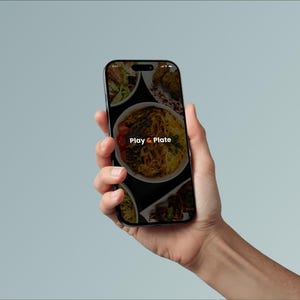 Peut inclure: Un smartphone affiche une interface d'application de restauration avec divers plats sur fond noir. Le logo de l'application, "Play & Plate", est visible. Le téléphone est tenu sur un fond bleu clair.
