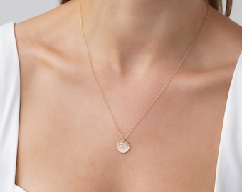 Peut inclure: Un collier en chaîne dorée avec un pendentif rond. Le pendentif a une surface texturée.