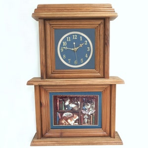 May include: A wooden wall clock with a blue face and gold hands. The clock has a picture of cats in a library below the clock face.