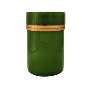 May include: A cylindrical green glass container featuring a smooth, translucent finish and a decorative gold-toned metal band encircling the middle. The vessel has a flat top and a straight-sided profile with subtle vertical indentations.