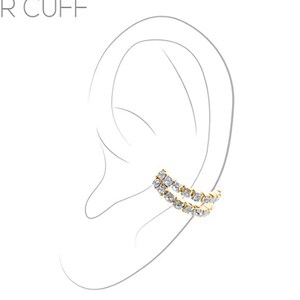 May include: A gold ear cuff with a double row of clear cubic zirconia stones. The cuff is designed to fit snugly on the upper part of the ear.