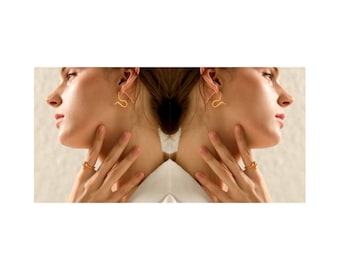 Peut inclure: Une femme portant des boucles d'oreilles en or et une bague en or à son doigt. Les boucles d'oreilles sont en forme de serpent.