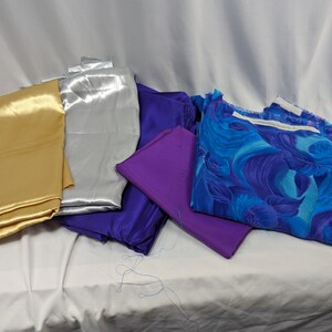 May include: Assortment of fabric swatches in gold, silver, purple, and blue floral print.