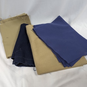 May include: A stack of fabric scraps in beige and navy blue. The fabric is folded and ready for a sewing project.