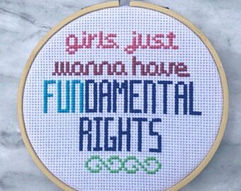 Könnte beinhalten: Ein Kreuzstich-Stickrahmen mit dem Text "girls just wanna have FUNDAMENTAL RIGHTS". Der Text ist in verschiedenen Farben gehalten, darunter Rot, Burgunder, Blau und Grün. Die Stickerei befindet sich in einem Holzreifen.