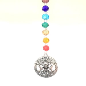 May include: A silver charm with a triple moon and pentacle design hangs from a crystal beaded chain. The beads are in rainbow colors, starting with purple and ending with red.