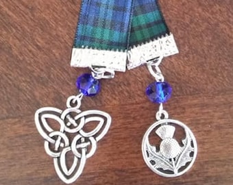 May include: A blue and green tartan ribbon bookmark with silver charms. One charm is a Celtic knot and the other is a thistle.