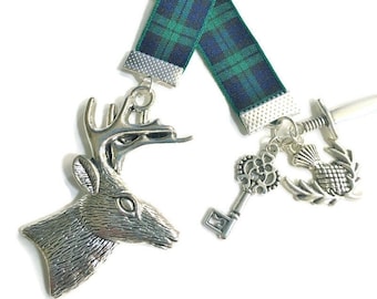 May include: A green and blue tartan ribbon bookmark with a silver stag head charm, a silver key charm, a silver thistle charm, and a silver sword charm.