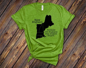 May include: A lime green t-shirt with a black graphic of the New England states and the text "New England Because Old England was wicked stupid." The shirt is made of a soft material and has rolled-up sleeves.