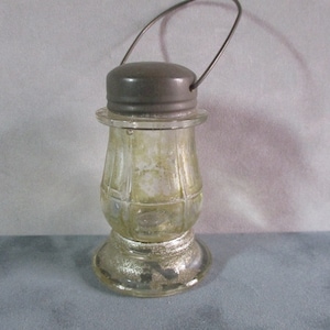 May include: A vintage glass lantern shaped candy jar with a silver lid and a wire handle. The jar has a textured glass design and a silver base.