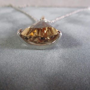 Peut inclure: Un collier en argent avec un grand pendentif en forme de larme facett&eacute;, transparent. Le pendentif est de couleur or et est serti dans une b&eacute;li&egrave;re en argent.