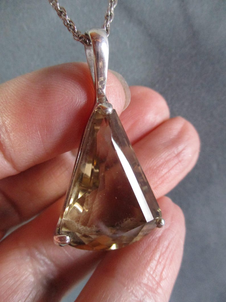 Peut inclure: Un collier en argent avec un pendentif en forme de larme orn&eacute; d'une grande pierre pr&eacute;cieuse brune facet&eacute;e.