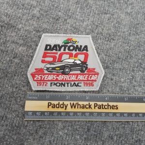 May include: A gray and red patch commemorating the 38th Daytona 500 race. The patch features a black car, the text "25 YEARS-OFFICIAL PACE CAR", and the years "1972 PONTIAC 1996". The patch is approximately 3 inches wide.