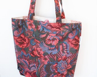 May include: A floral tote bag with a pink, blue, and green pattern. The bag has a white lining and a small label on the side that says "handmade".