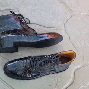 May include: Two pairs of black leather ankle boots with crocodile print. The boots have laces and a chunky heel.