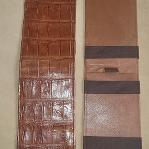 Puede incluir: Dos carteras de cuero marr&oacute;n, una con un patr&oacute;n de cocodrilo en relieve y el texto "M. Slaughter" grabado en la parte inferior, y la otra con dos bandas el&aacute;sticas.