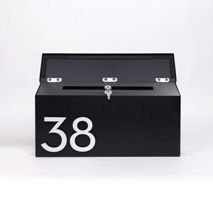 May include: Black metal mailbox with a white number "38" on the front. The mailbox has a hinged lid and a keyhole.