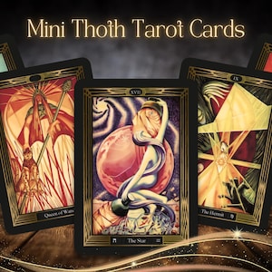 Może przedstawiać: Karty Mini Thoth Tarot z szczegółowymi ilustracjami w różnych kolorach. Karty mają czarne obramowania ze złotymi akcentami. Centralna karta przedstawia postać z różową kulą i tekstem "The Star".