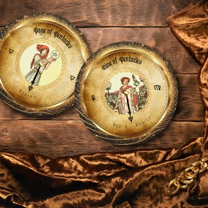 May include: Two round, antique-style tarot card designs with gold frames and illustrations of figures. The cards are set against a wooden background with a brown velvet cloth and a gold chain. The text on the cards reads "Page of Pentacles" and "Nine of Pentacles."