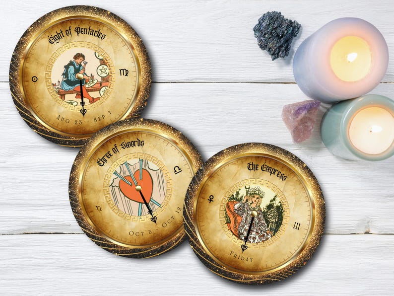 May include: Three round tarot card coasters with gold glitter rims. The coasters feature illustrations of the Eight of Pentacles, Three of Swords, and The Empress. Candles and crystals are in the background.