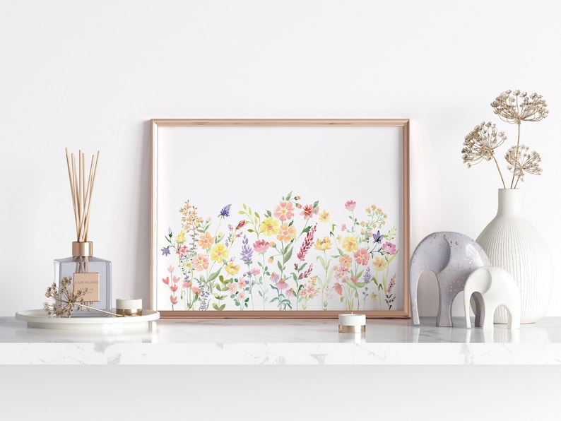 May include: A framed watercolor painting of a field of wildflowers in shades of pink, yellow, and purple. The flowers are arranged in a horizontal line across the canvas, with a few butterflies flying above them.