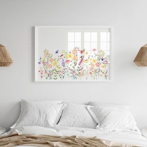 May include: A white framed watercolor painting of a field of colorful wildflowers. The painting is hanging on a white wall above a white bed with white bedding.