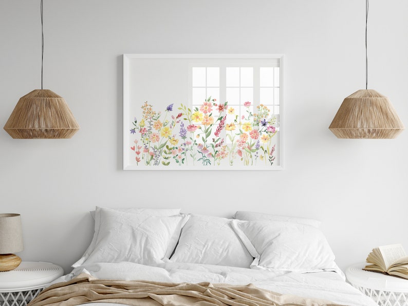 May include: A white framed watercolor painting of a field of colorful wildflowers. The painting is hanging on a white wall above a white bed with white bedding.