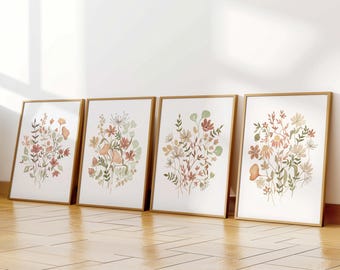 May include: Four framed prints featuring watercolour illustrations of floral bouquets in shades of brown, pink, and green. The prints are arranged in a row on a wooden floor.
