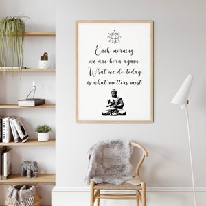 May include: A framed print with a black and white image of a meditating Buddha and a quote that reads "Each morning we are born again. What we do today is what matters most."
