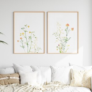 May include: Two framed watercolor prints of wildflowers with green stems and yellow, orange, and pink flowers on a white background.