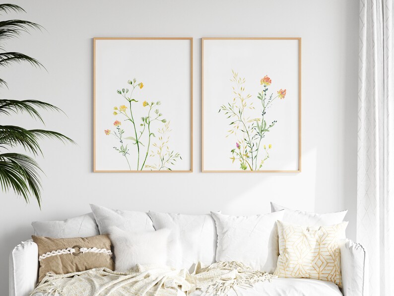 May include: Two framed watercolor prints of wildflowers with green stems and yellow, orange, and pink flowers on a white background.