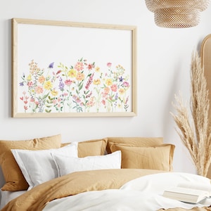May include: A framed watercolor print of a floral arrangement featuring pink, yellow, and purple flowers on a white background. The print is in a light wood frame and is hanging on a white wall.