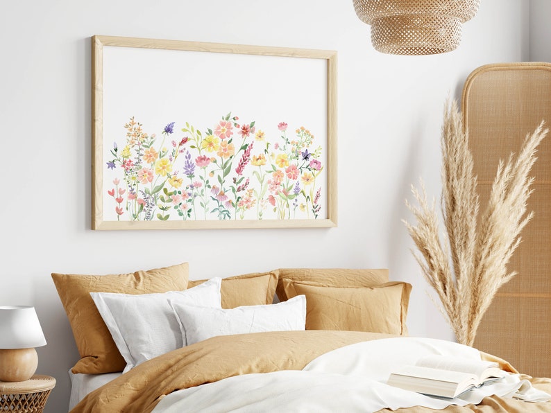 May include: A framed watercolor print of a floral arrangement featuring pink, yellow, and purple flowers on a white background. The print is in a light wood frame and is hanging on a white wall.